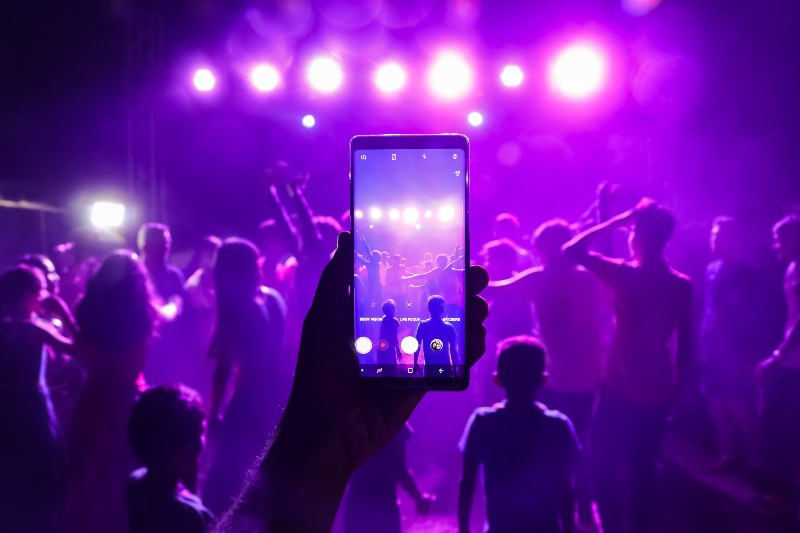 5 Easy Ways to Get DJing Gigs - music fans taking photos at a gig