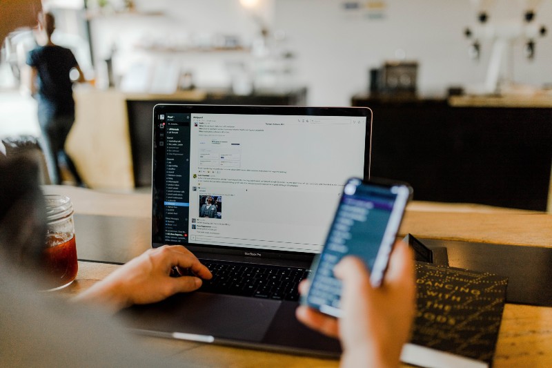 5 Easy Ways to Get DJing Gigs - person using their laptop and mobile to check messages
